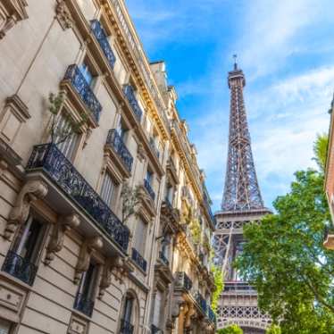 A view of the Eiffel Tower from a Parisian street on a sunny day.