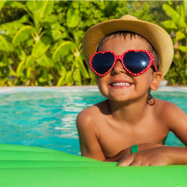A child in a swimingpool wearing sunglasses