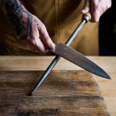 Professional chef sharpening knife in the kitchen