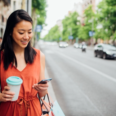 Woman holding a cup of coffee and looking at mobile phone 