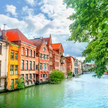 A row of colourful houses along a Ghent canal on a sunny day.