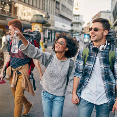 Smiling young people wearing sunglasses walking through a shopping street