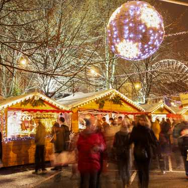 A bustling Christmas market on the streets of Lille at night.