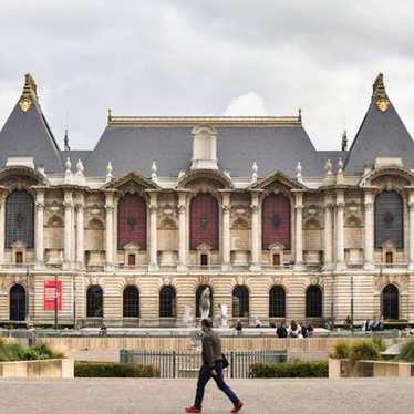 A view of people walking in front of the Palais des Beaux Artes.