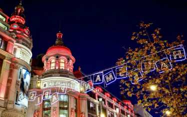 Ein hausgemachtes Gebäude mit roter und weißer Weihnachtsbeleuchtung, ein festliches Banner, das einen magischen Weihnachtsmarkt in Paris ankündigt, der mit einem direkten Eurostar-Zug leicht erreichbar ist.