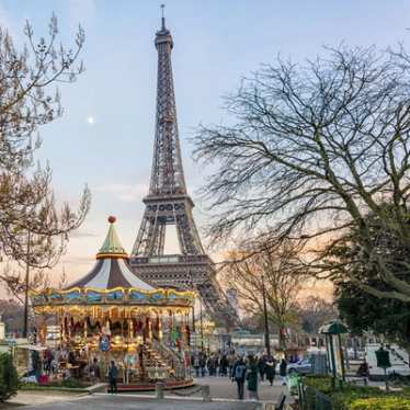 Paris im Winter: Ein Blick auf den Eiffelturm mit einem alten, erleuchteten Karussell davor.