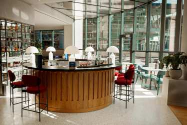 Ce luxueux bar à cocktails circulaire situé à l'intérieur de la gare de Bruxelles-Midi propose des sièges en velours aux tons profonds, disposés autour d'un comptoir circulaire aux lignes épurées et aux accents métalliques polis.