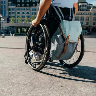 Man using wheelchair with bag in city