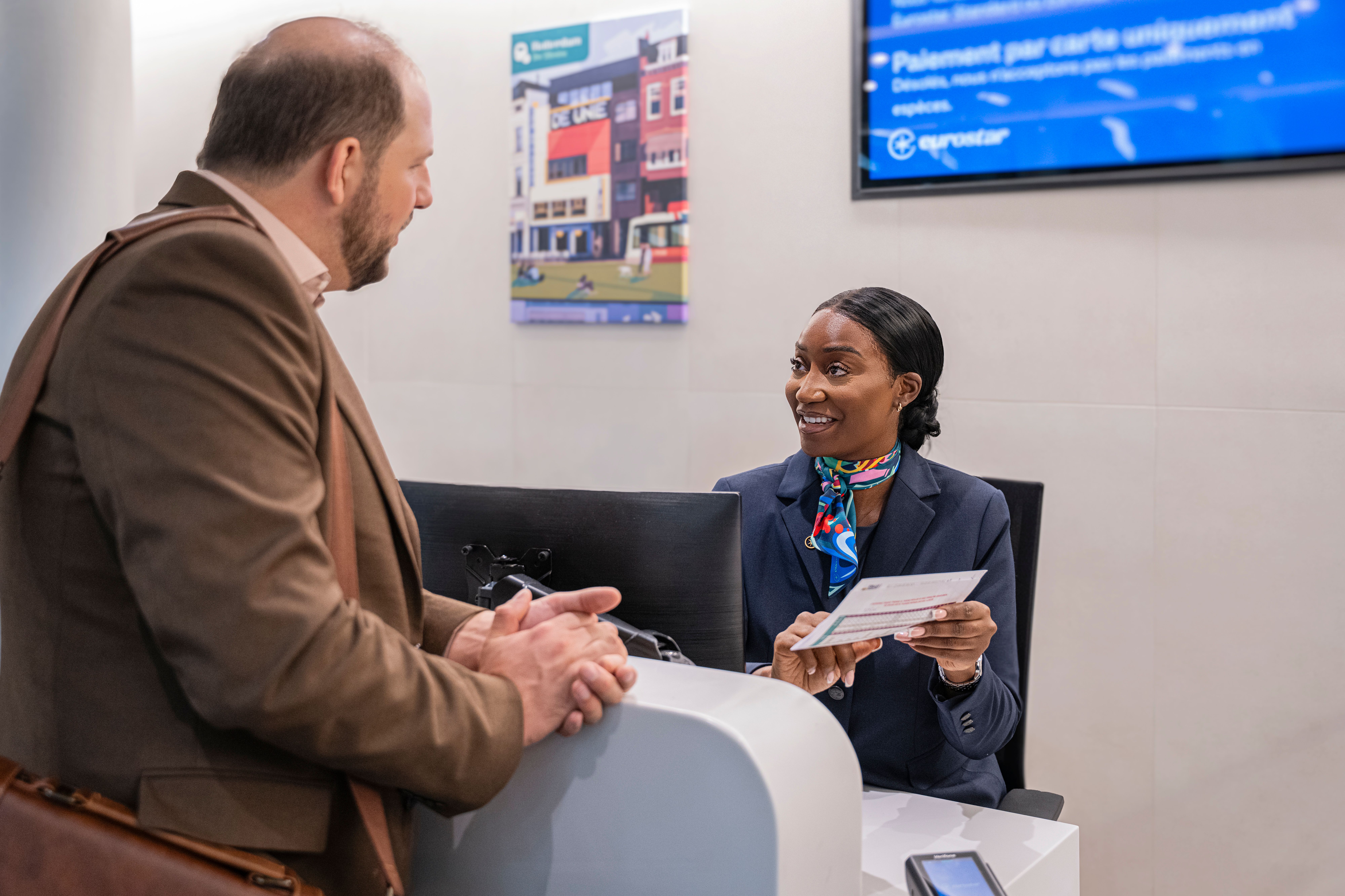 Een reiziger spreekt met een medewerker aan een servicebalie.