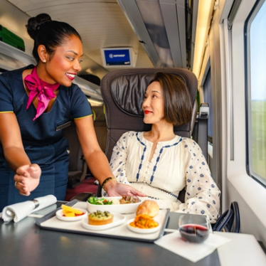 A member of the onboard team serving a passenger a meal in Eurostar Premier on board an e320.