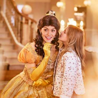 A child telling the Disney character Belle a secret in Disneyland Paris.