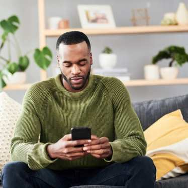 Man sitting on the sofa using his phone at home