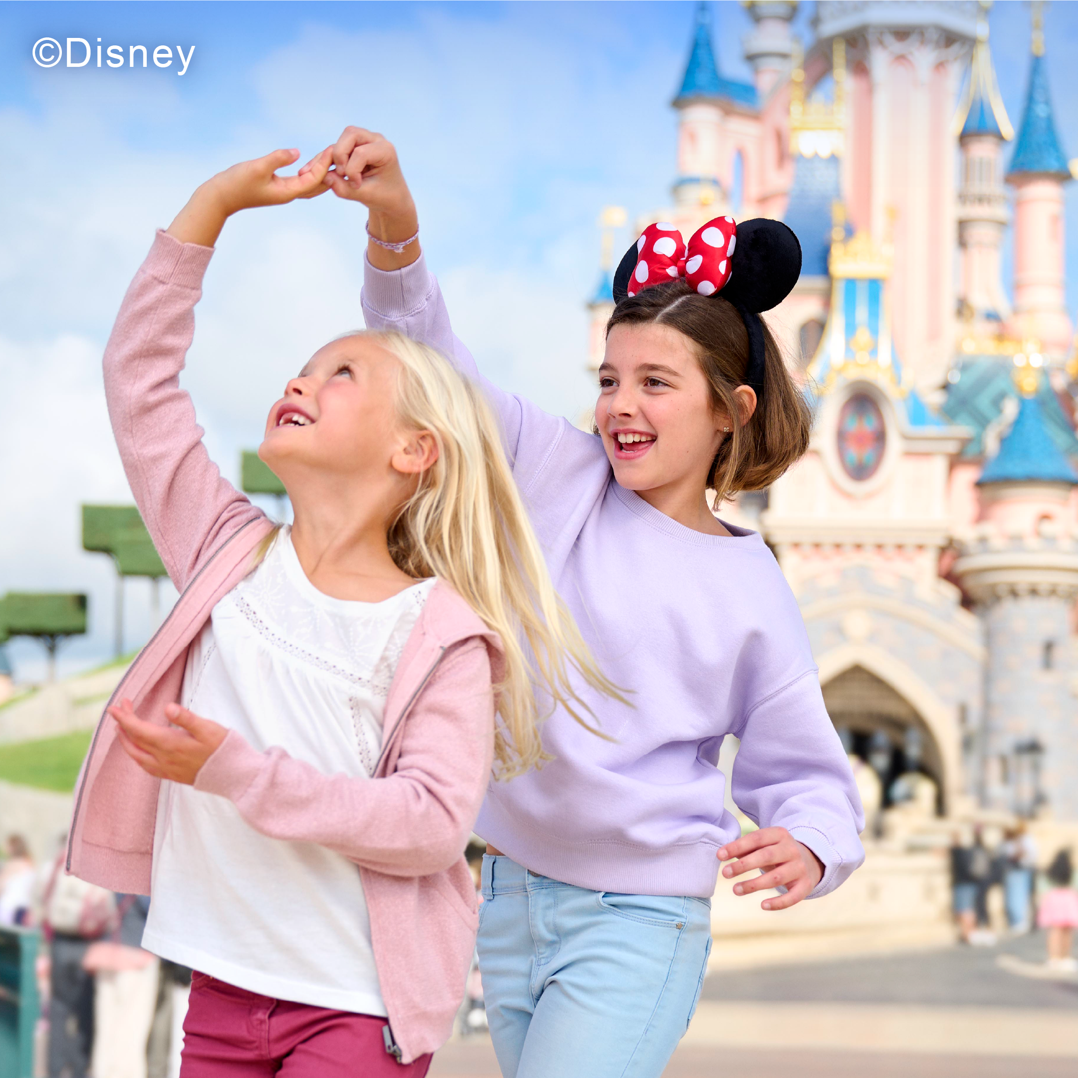 Young girls playing in front of the Disneyland Paris castle.