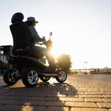 Woman riding a four wheel mobility electric scooter - accessible travel - accessibility
