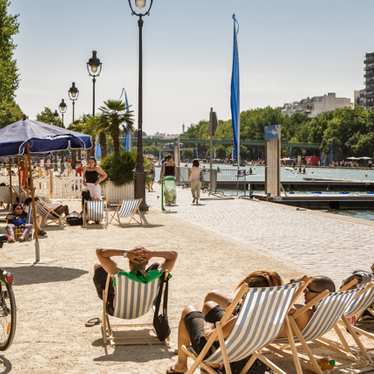People tanning on sunloungers by the side of the canal in the summer