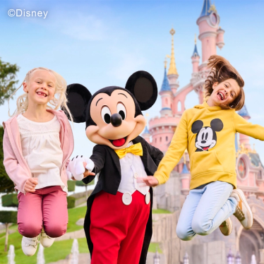 Mickey Mouse and children jumping in front of the Disneyland Paris castle.