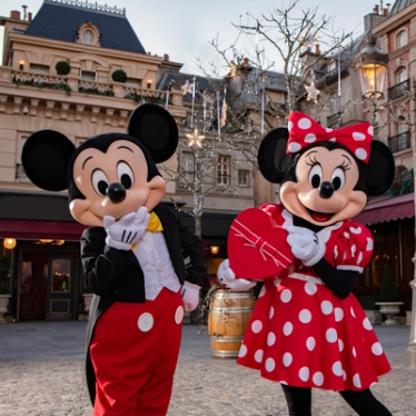 Mickey Mouse excited, holding his hand to his mouth, and Minnie Mouse standing next to him holding a heart-shaped chocolate box. Both are smiling, excited about sharing the love this february with Eurostar and Disney. 