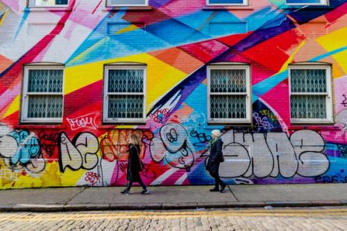 Two people walking down a graffitied east London street