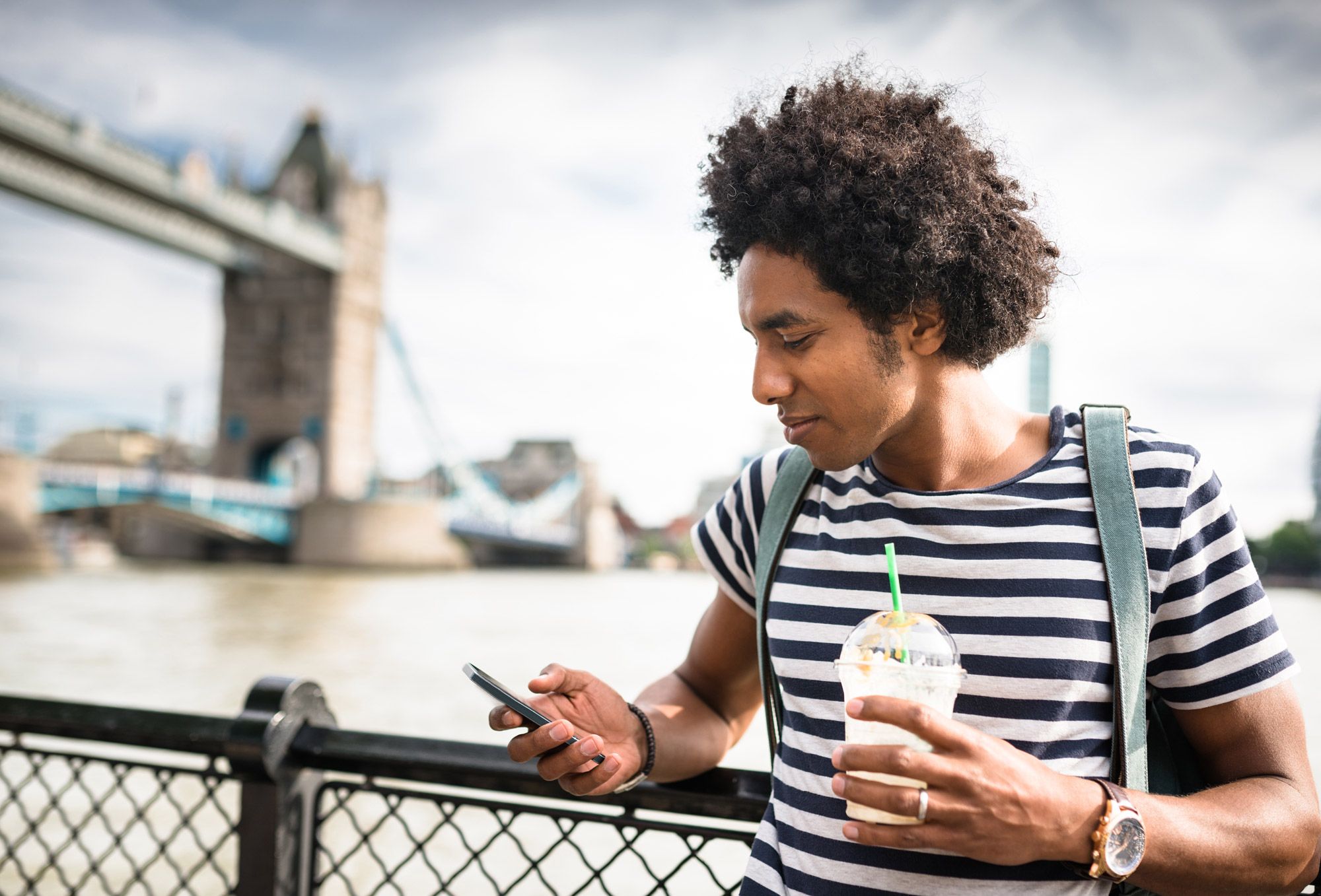 Man looking at his phone with Tower bridge in the background