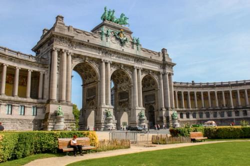 A woman sitting on a bench in Parc du Cinquantenaire in Brussels on a sunny day.