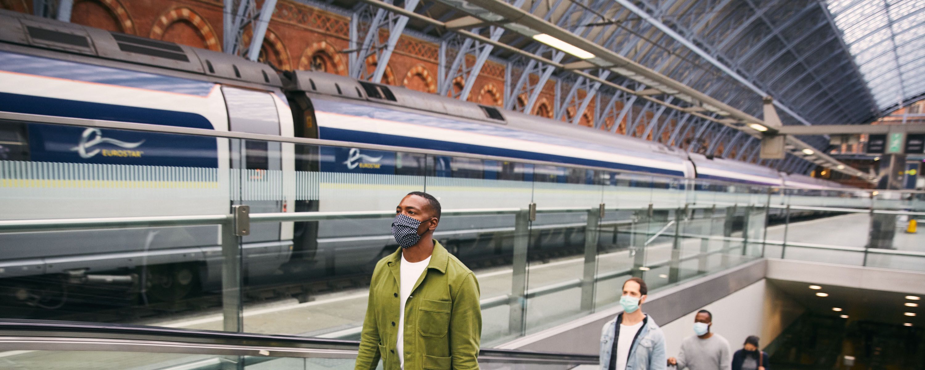 Man wearing a mask travelling up the escalators in London St Pancras
