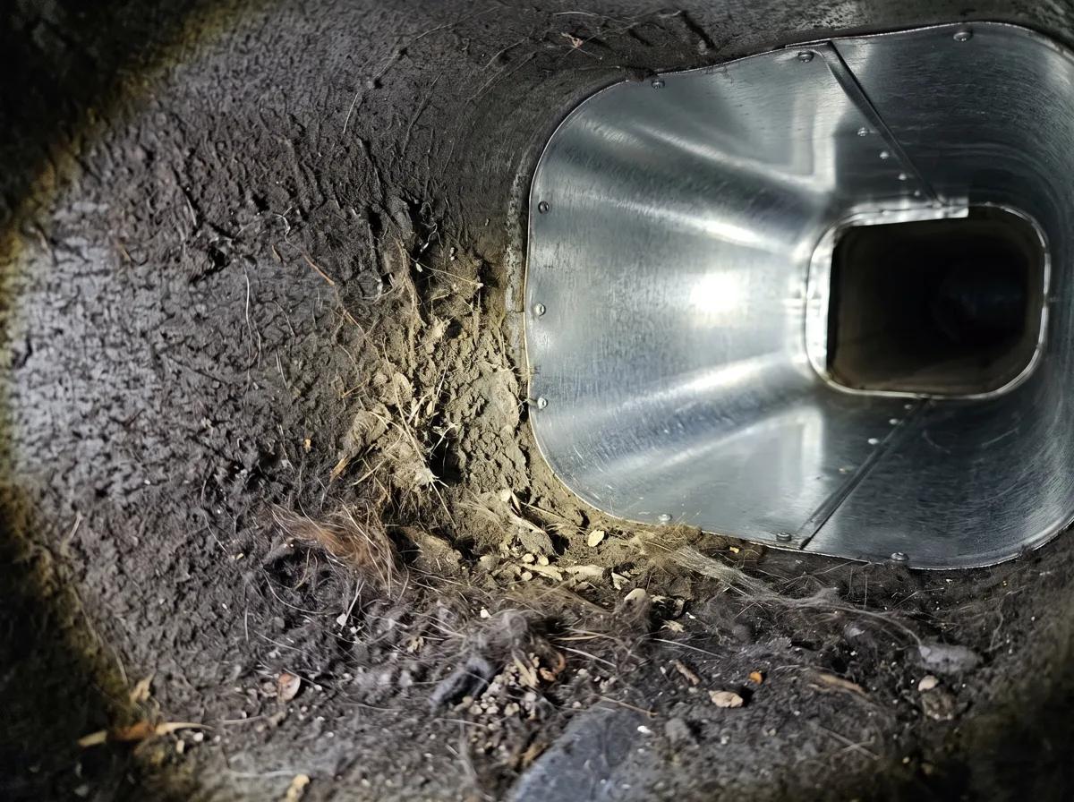 Dust and debris visible inside a floor register, a common sign that air ducts need cleaning