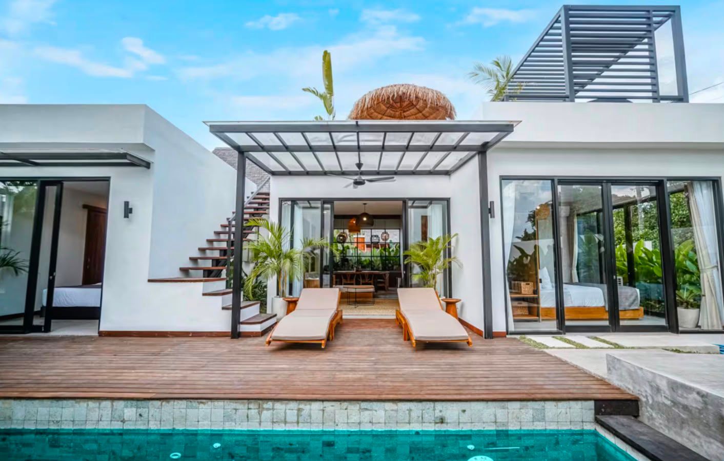 Villa pool deck with sun loungers, timber decking, and tropical planting