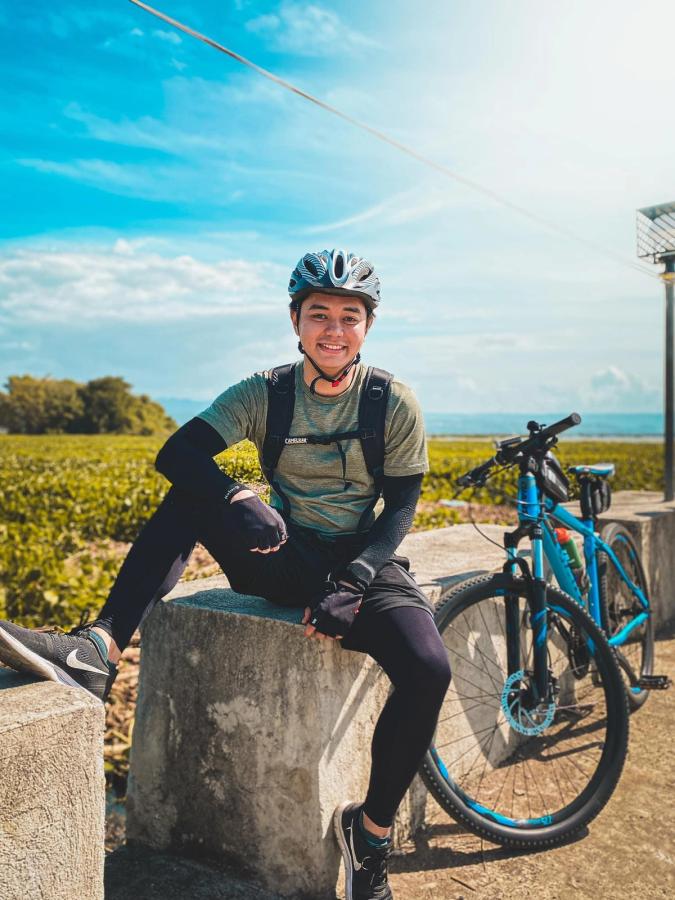 A man in cycling apparel sitting beside a blue bike