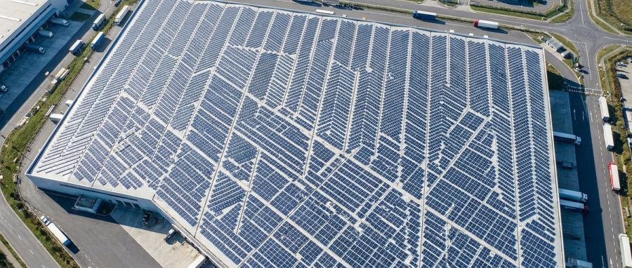 Aerial view of a warehouse roof covered in solar panels