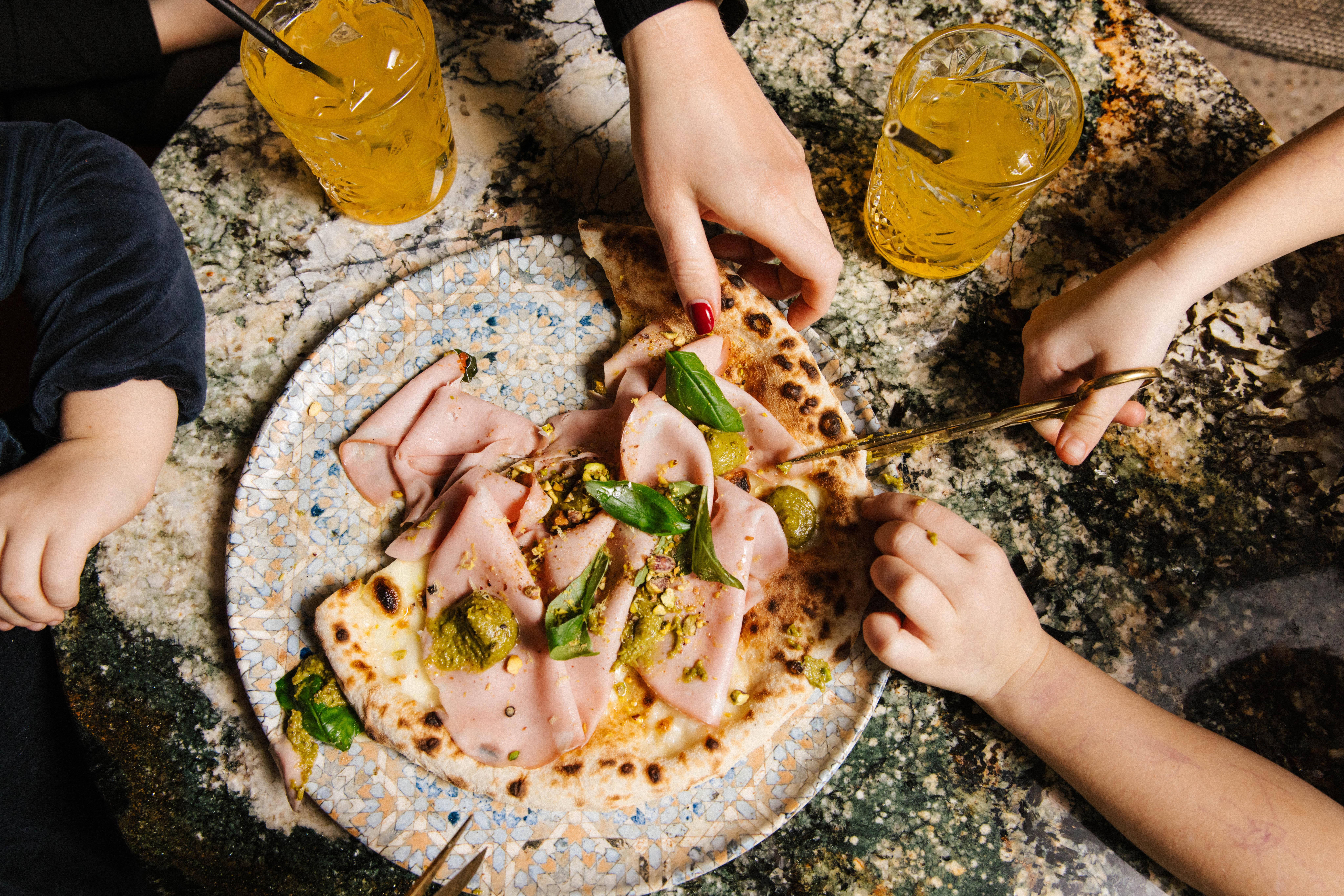 Hender som forsyner seg med pizza fra en tallerken