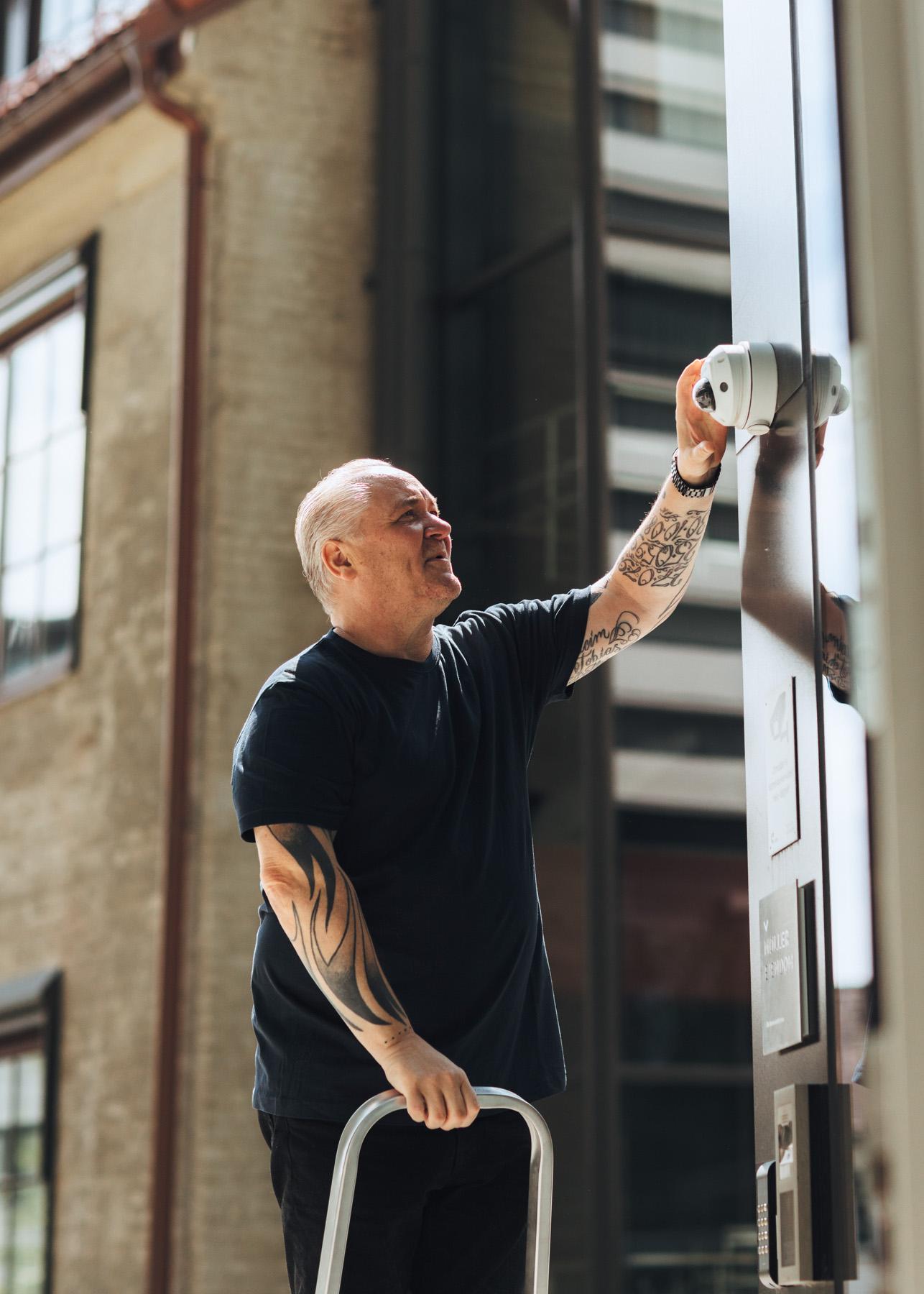 Man on ladder repairs camera