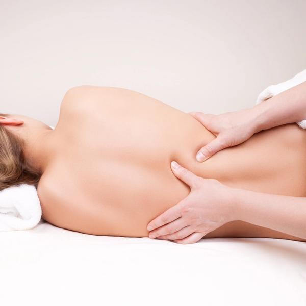 Liggende kvinne får ryggmassasje