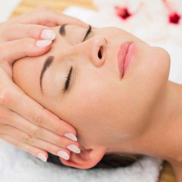 Kvinne med lukkede øyne får ansiktsmassasje