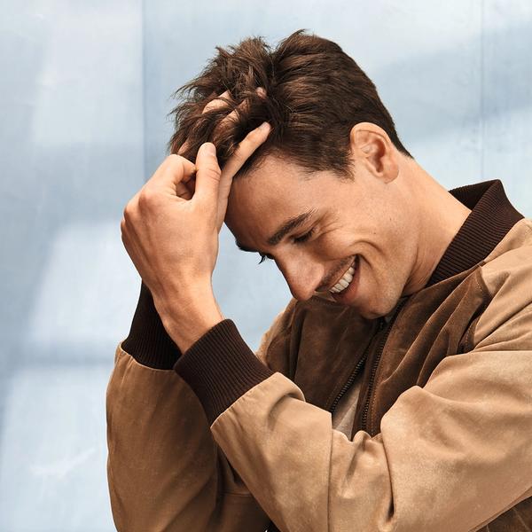 Ung mann med kort hår som smiler og tar seg i håret