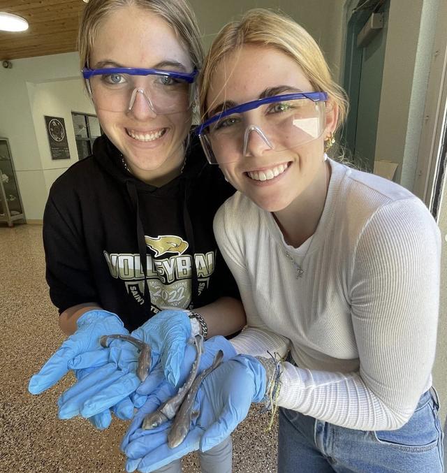 Two students examine a specimen at the marine science lab tank