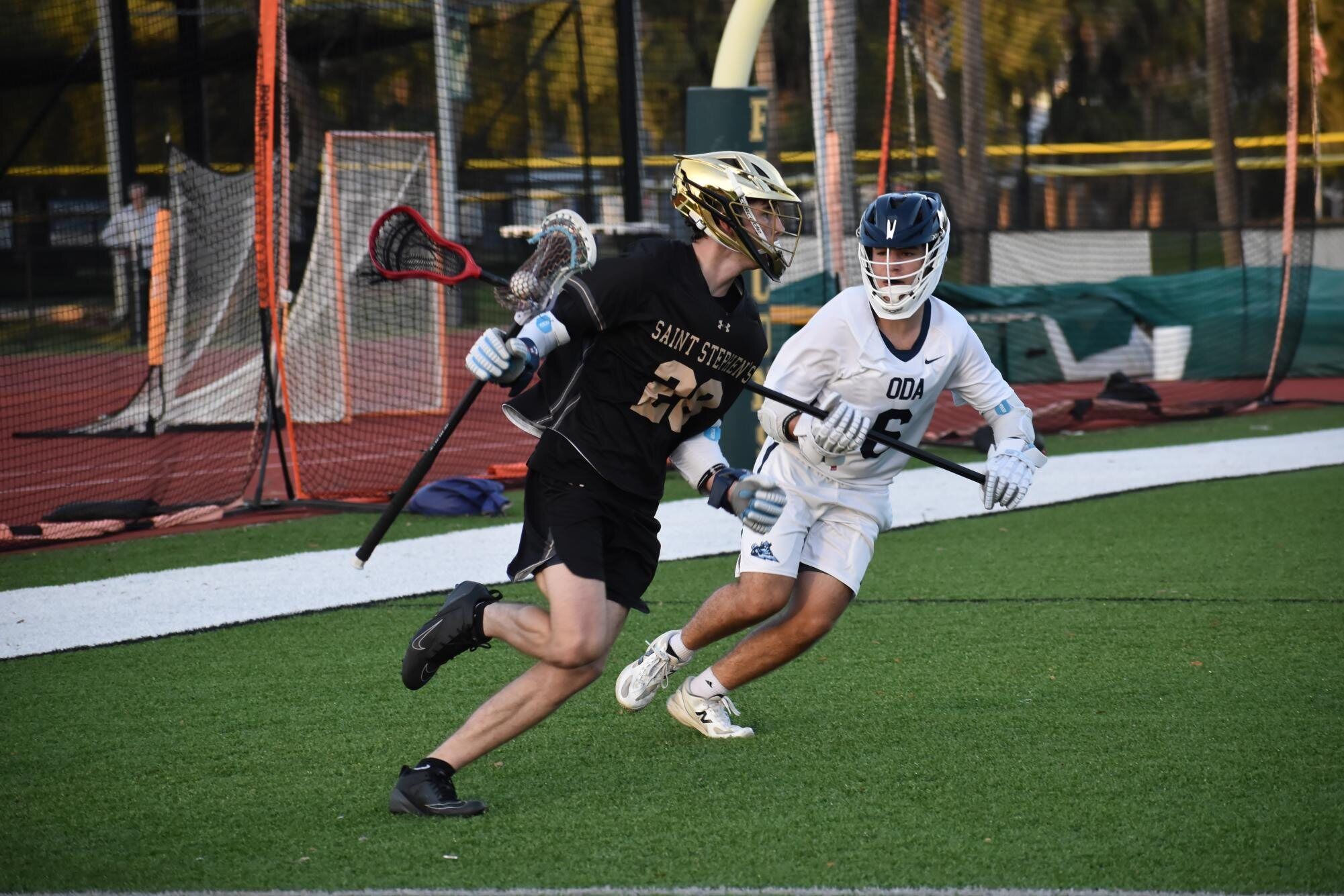 A boys' lacrosse player drives past an opposing defender during a game.