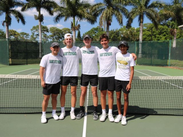 The boys' tennis team poses together at the net on the Saint Stephen's courts.