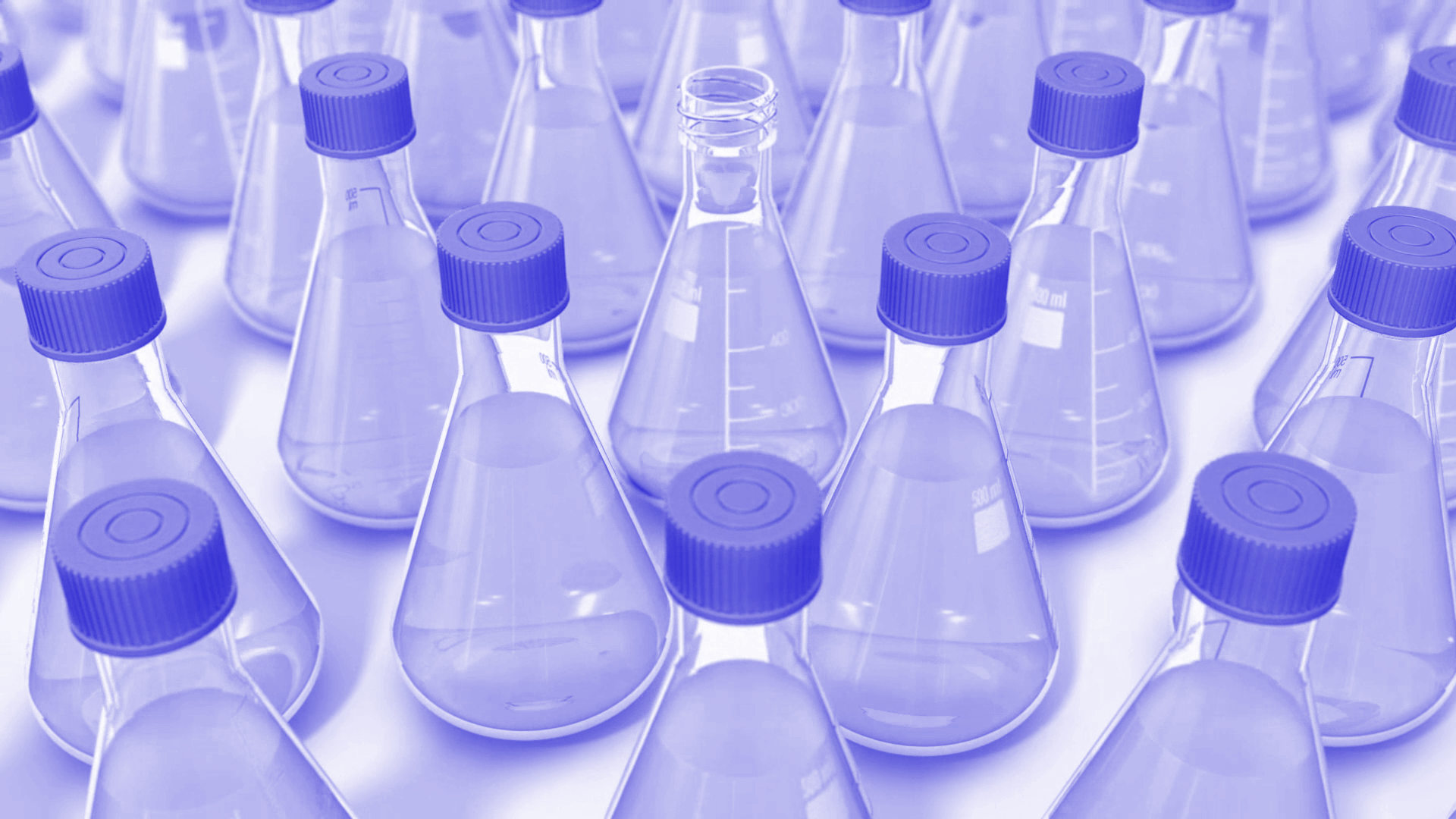 A series of pharma flasks with periwinkle liquids; one is missing a cap. 