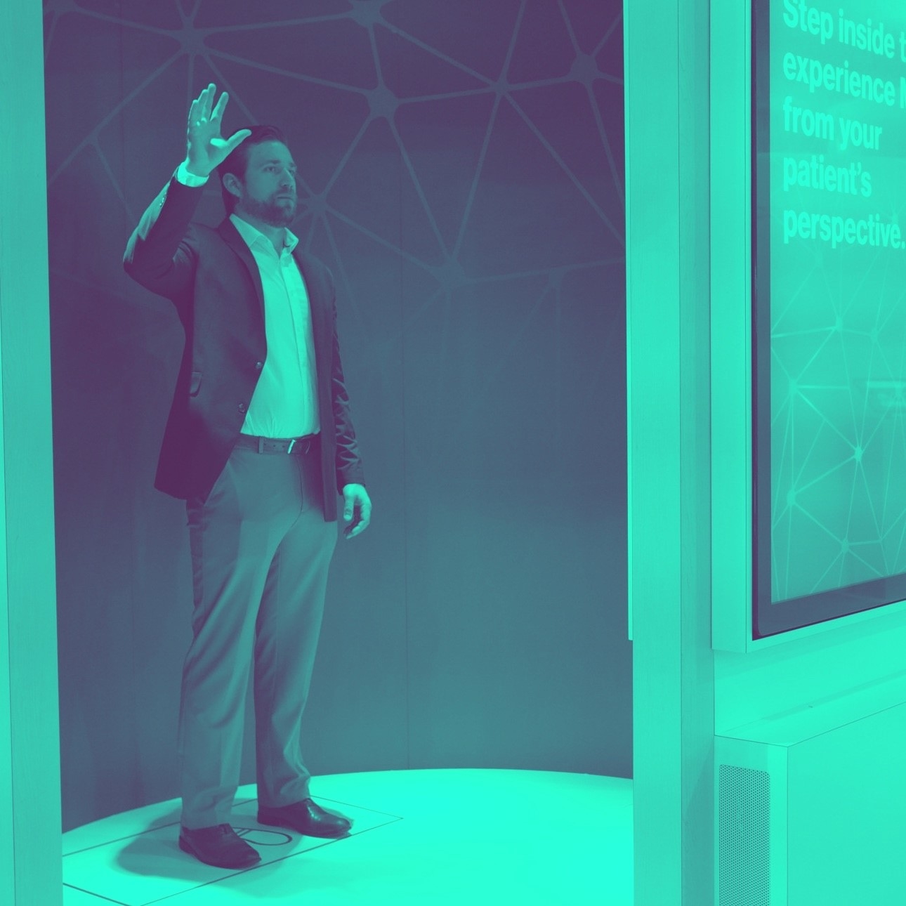 Duotone teal photo of a man in a booth gesturing, which is sensed by the Magic Leap to interact with the inner wall of the booth. 