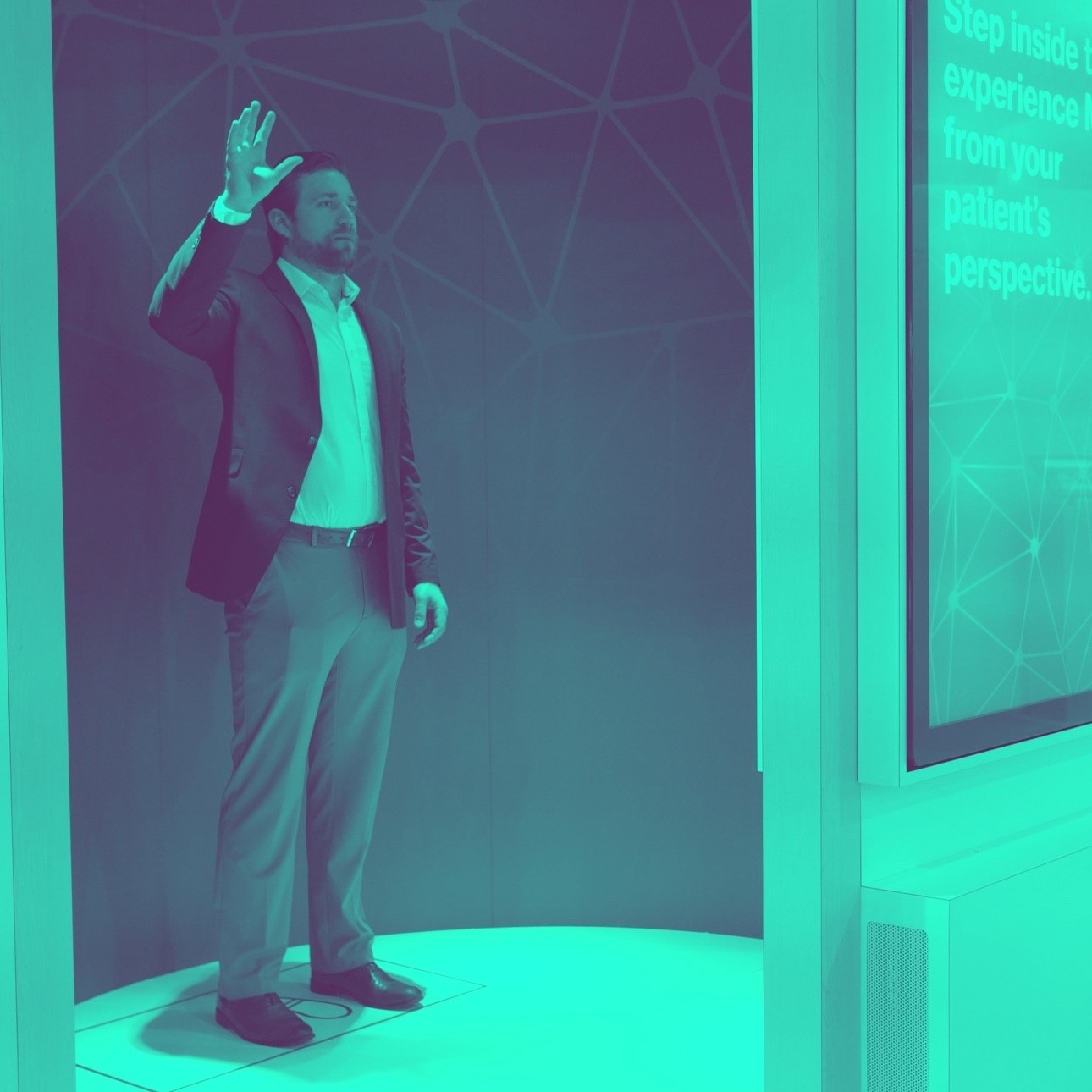 Duotone teal photo of a man in a booth gesturing, which is sensed by the Magic Leap to interact with the inner wall of the booth.
