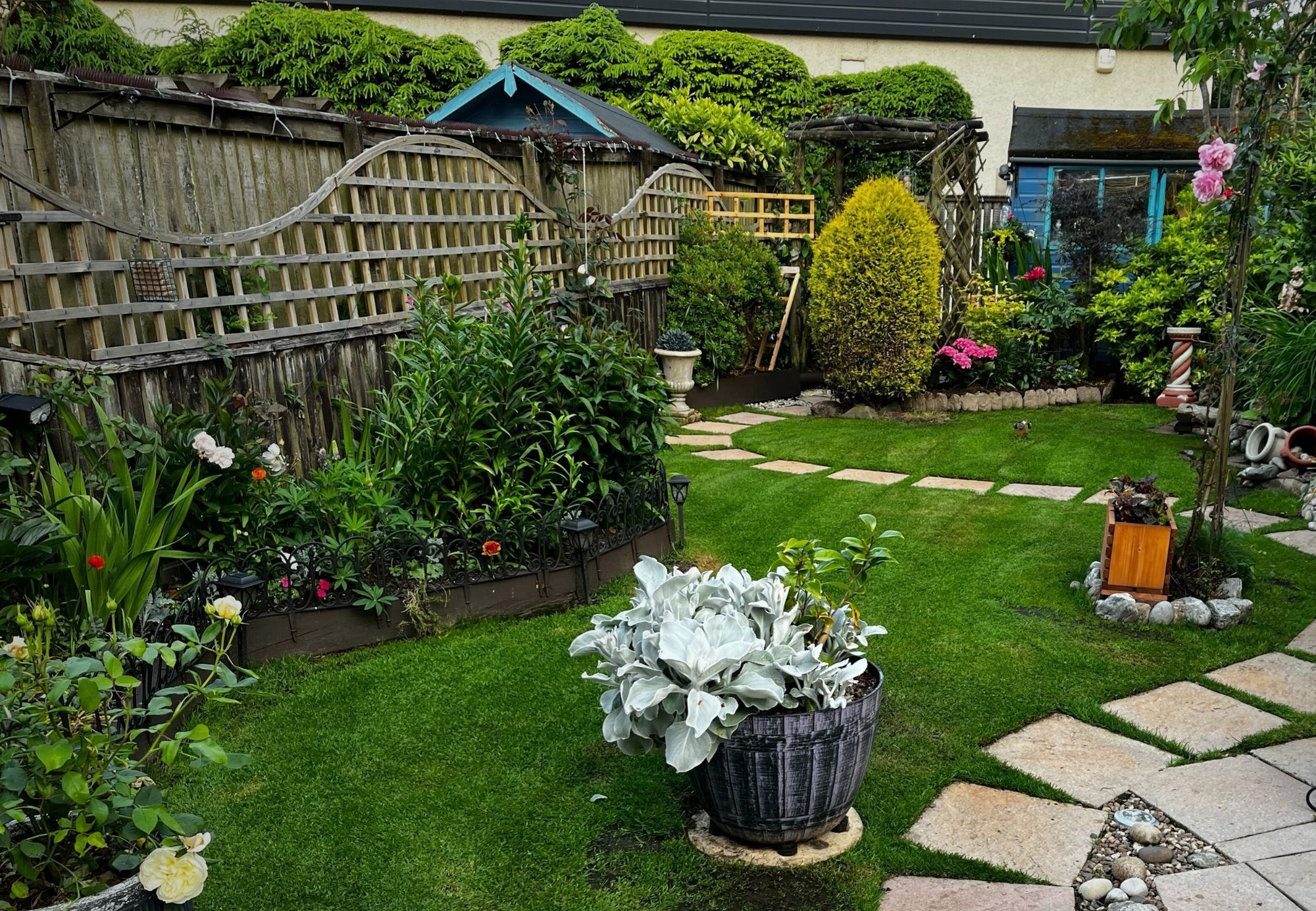 Small landscaped garden with stone path, lush lawn and flower beds