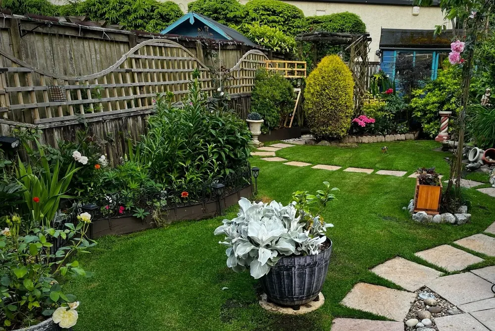 Small landscaped garden with stone path, lush lawn and flower beds