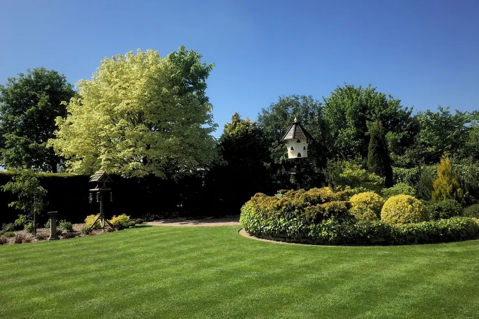 Beautifully striped lawn in a landscaped garden with shrubs and summerhouse