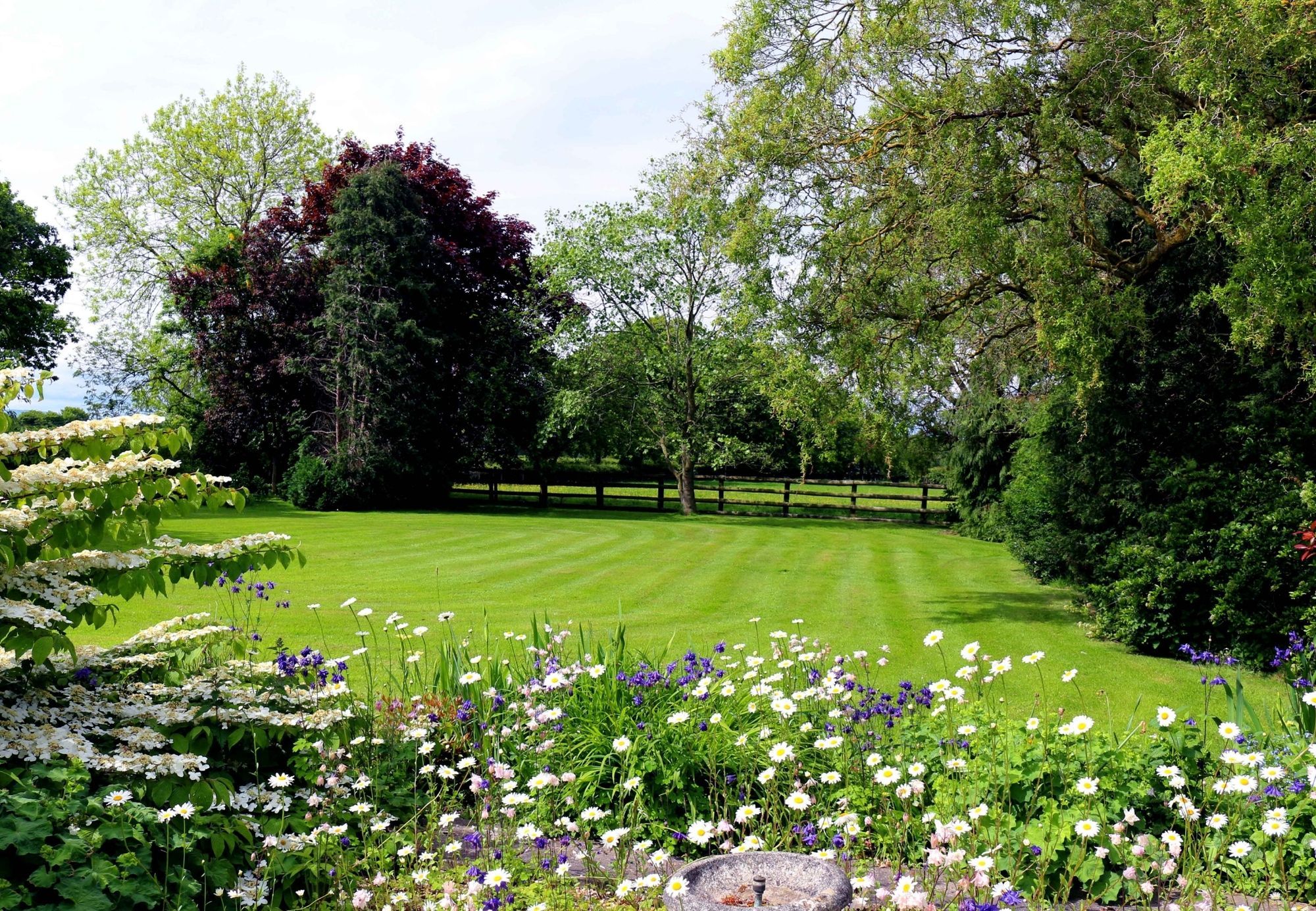 Open lawn with countryside backdrop and wildflower border