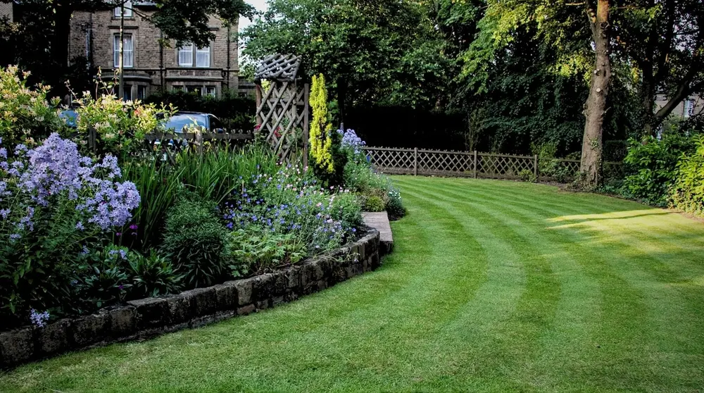 A neatly mown garden lawn with flower borders used as the banner image for the My.GreenThumb Activation page.