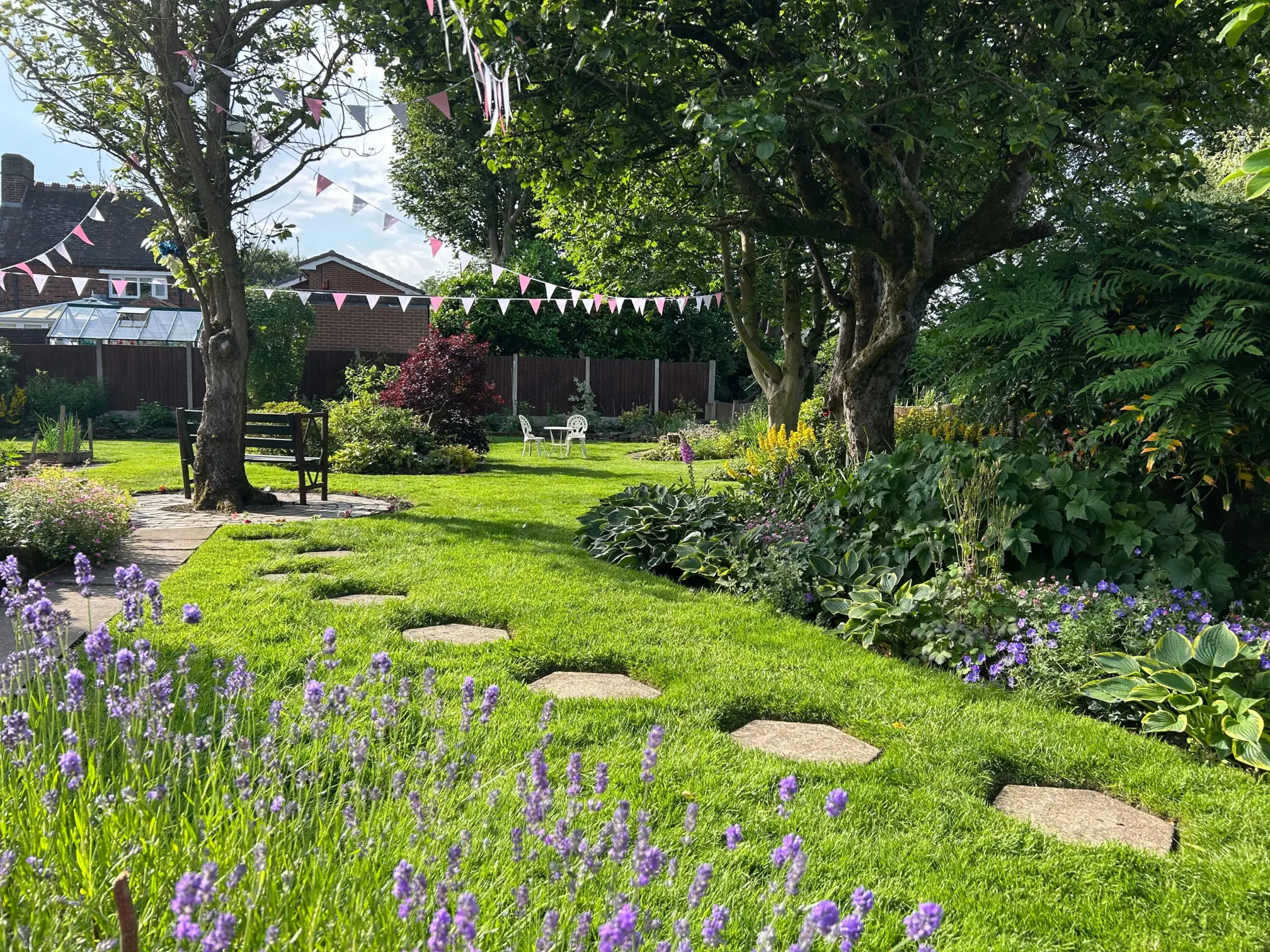 lush grass treated by GreenThumb with stone path and lavender border