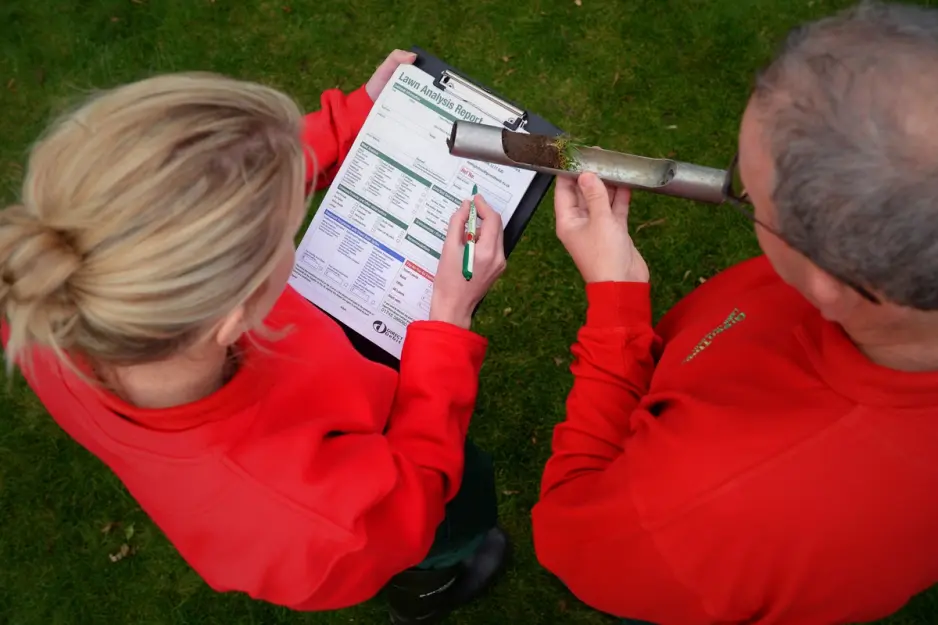 GreenThumb lawn care professional conducting a thorough lawn analysis to assess soil and grass health for optimal tr