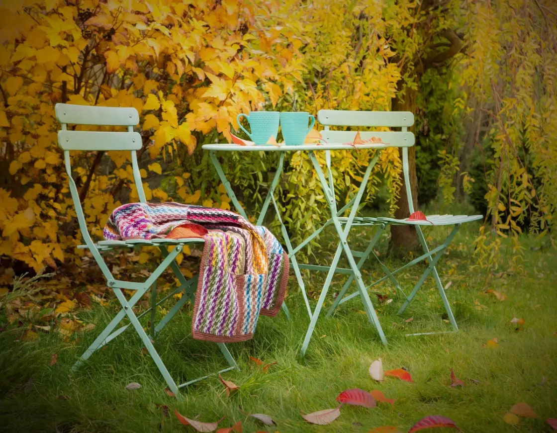 Garden table and chairs left on a lawn covered with autumn leaves, causing potential damage to grass