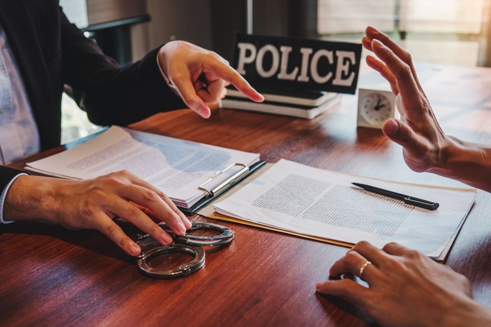 Person raising hand to stop police questioning during a criminal investigation in Florida with documents and handcuffs on table
