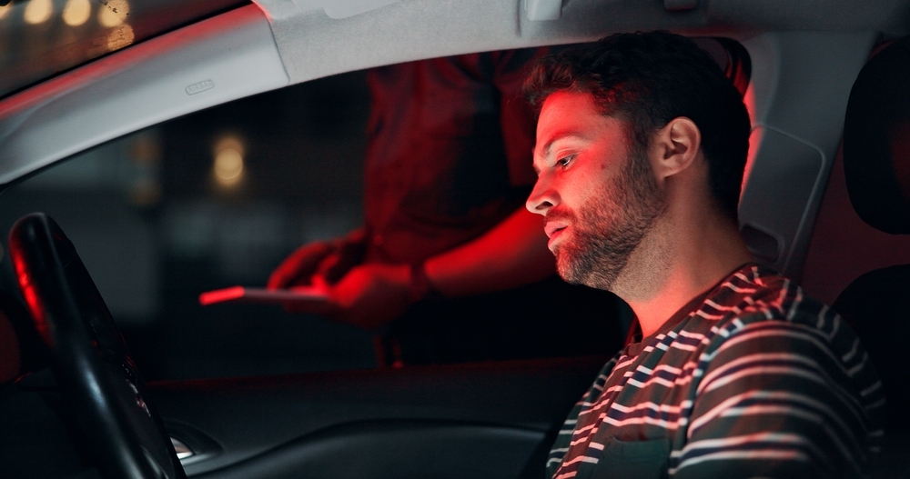 Image Driver stopped at night during a Thanksgiving Eve DUI traffic stop in South Florida, illuminated by red police lights as an officer stands beside the vehicle.